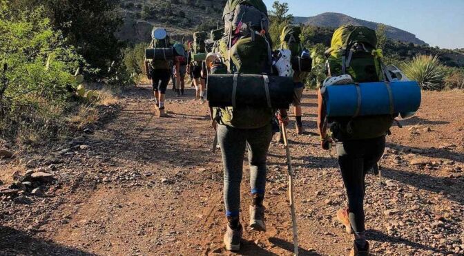 Group of students with backpacks and bed rolls hiking in New Mexico