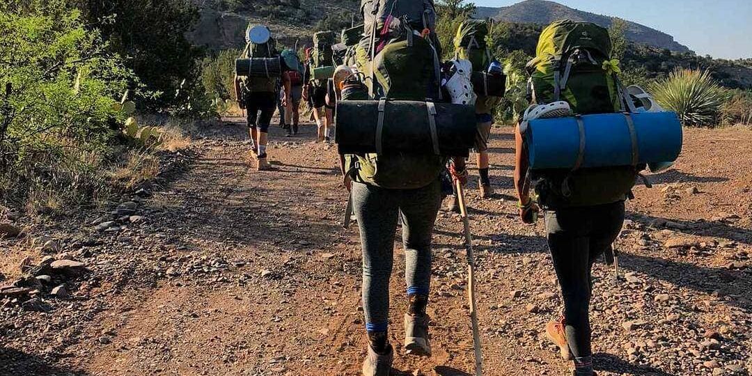 Group of students with backpacks and bed rolls hiking in New Mexico